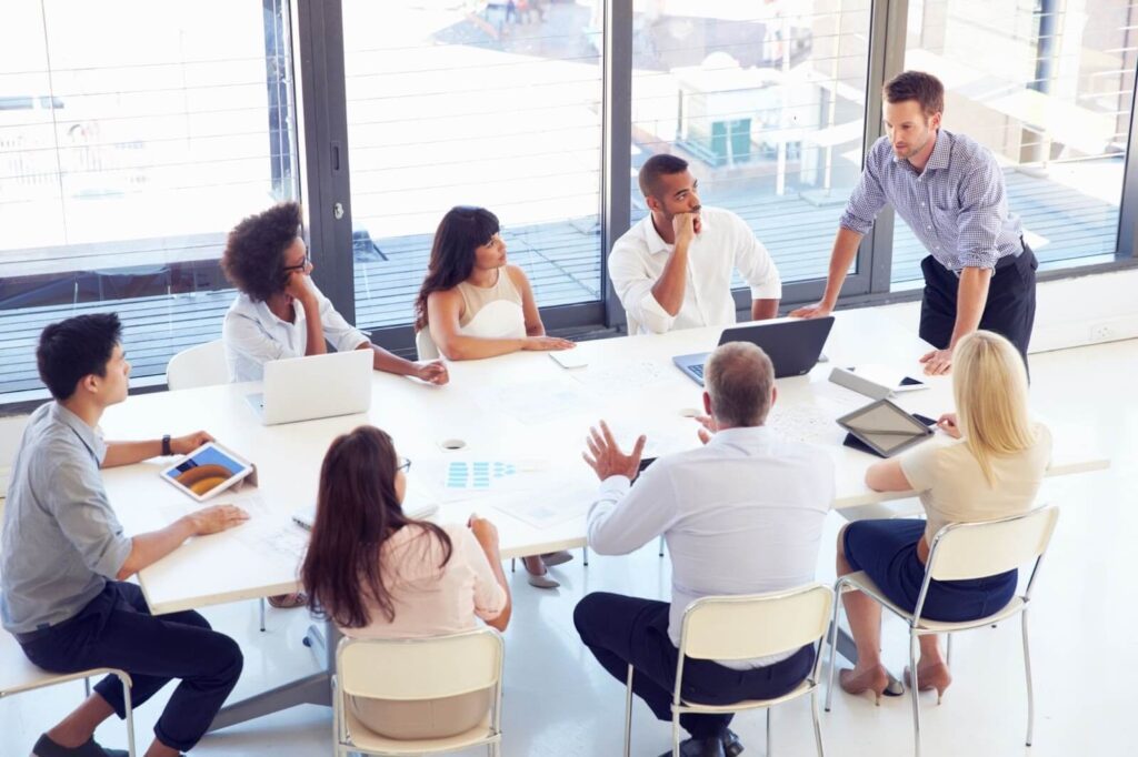 A group of people around a table exchanging advice. ( mastermind community )